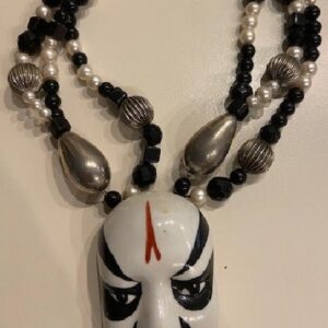 A necklace with a black and white mask on it.