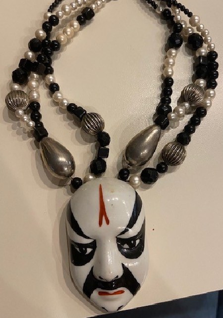 A necklace with a black and white mask on it.
