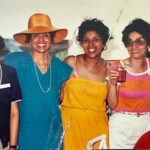 Four women standing next to each other at a party.