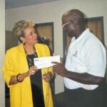 A man and woman standing next to each other holding a check.