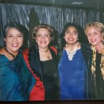 Four women posing for a photo at a party.