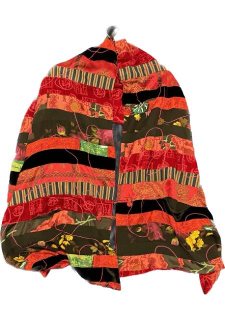 A red, orange, and black Designer Garment 25 quilted blanket.