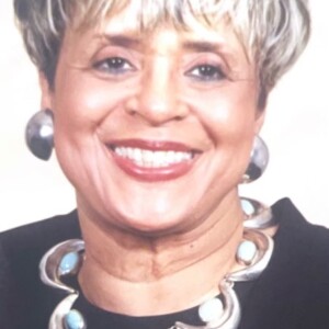 A smiling woman wearing a black top and necklace.