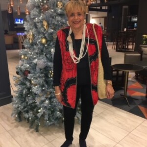 A woman standing in front of a christmas tree.