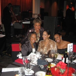 Four women posing for a picture at a dinner table.