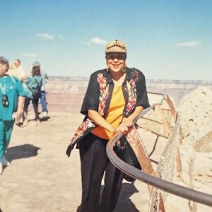 A woman standing on a railing at the grand canyon.