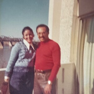 A man and woman standing on a balcony next to a river.