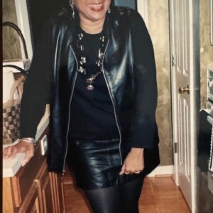 A woman wearing a black leather jacket and skirt.