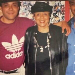 Three people posing for a photo in front of a wall.