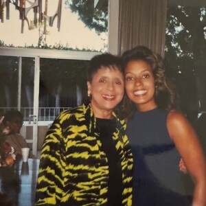 Two women posing for a photo in front of a table.