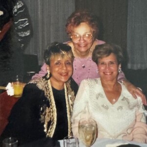 Three women posing for a picture at a table.