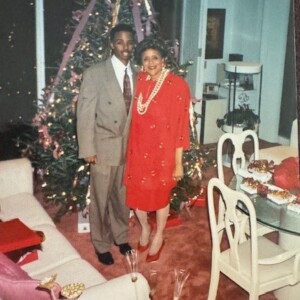 A man and woman standing in front of a christmas tree.