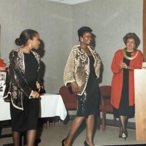 Three women standing in front of a table.