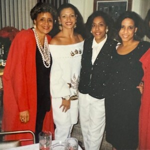 Four women posing for a picture in front of a table.