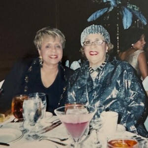Two women sitting at a table with glasses of wine.