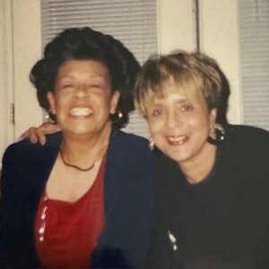 Two women sitting next to each other in front of a window.