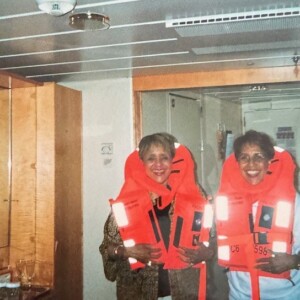 Two women in life jackets standing in a room.