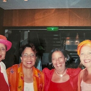 Three women in orange hats posing for a photo.