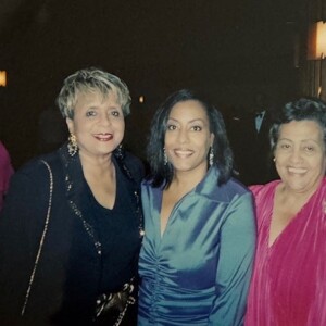 Three women posing for a photo in a pink dress.