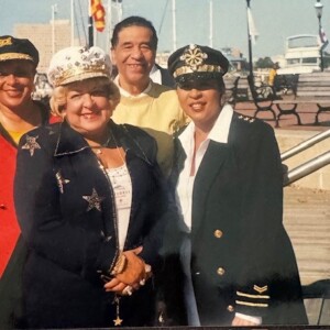 Four women in hats and uniforms posing for a photo.