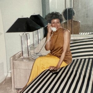 A woman sitting on a bed and talking on the phone.