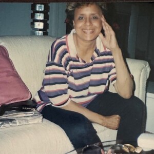 A woman in a striped shirt sitting on a couch.
