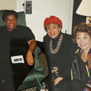 Three women posing for a picture in a hotel room.