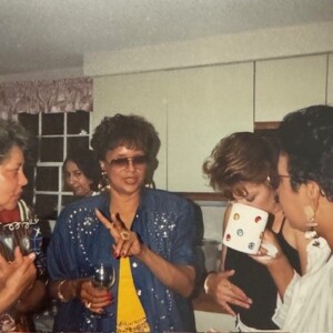 A group of women in a kitchen talking to each other.