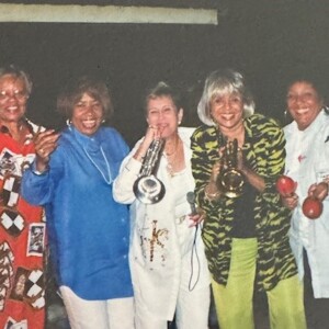 A group of women standing next to each other holding saxophones.