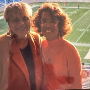 Two women posing for a picture in front of a stadium.