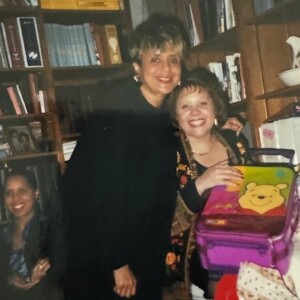 An old photo of a woman and a girl posing in front of a bookcase.