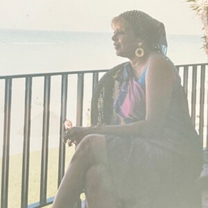 A woman sitting on a balcony overlooking the ocean.