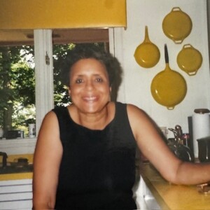 A woman sitting in a kitchen holding a plate.