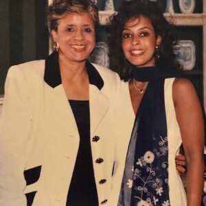 Two women posing for a photo in front of a wall.