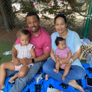 A man and woman sitting on a blanket with two small children.