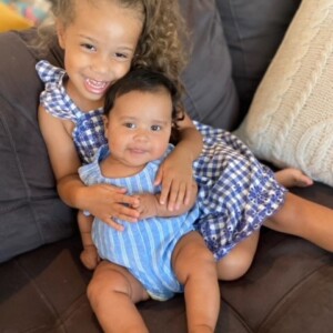 Two little girls are sitting on a couch together.