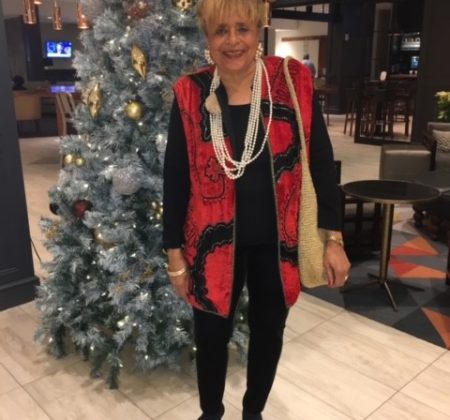 A woman standing in front of a christmas tree.